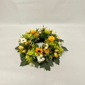 Wianek na znicz wykonany na plastikowym podkładzie z dodatkiem słonecznika, hortensji i róż